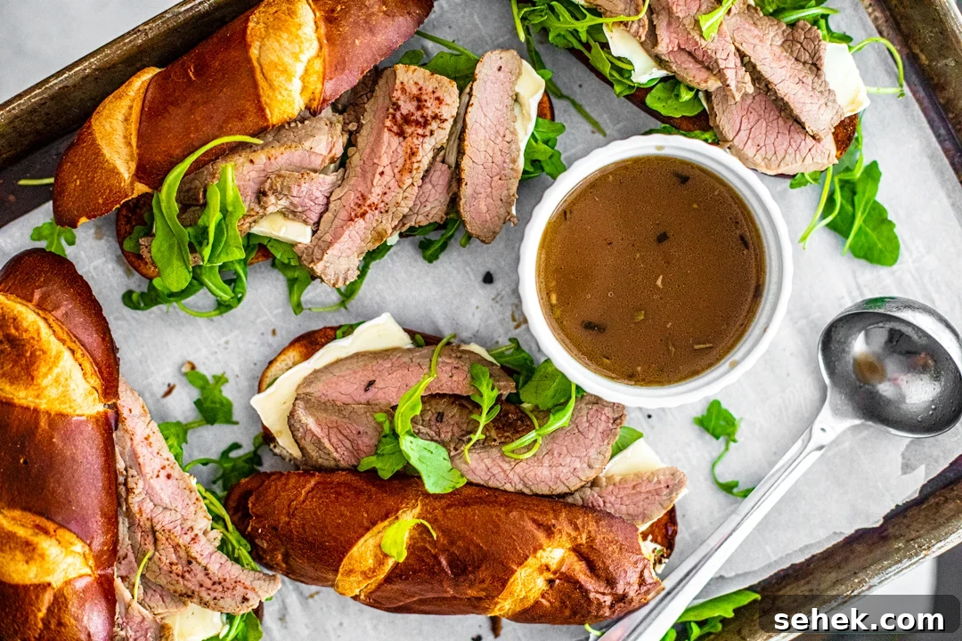 Brie and Roast Beef Sandwiches with Savory Au Jus 3 Overhead shot of baking sheet topped with brie and beef sandwiches.