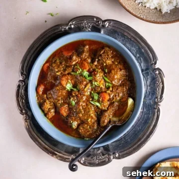 A bowl of beef masala in a tray on a flat surface.
