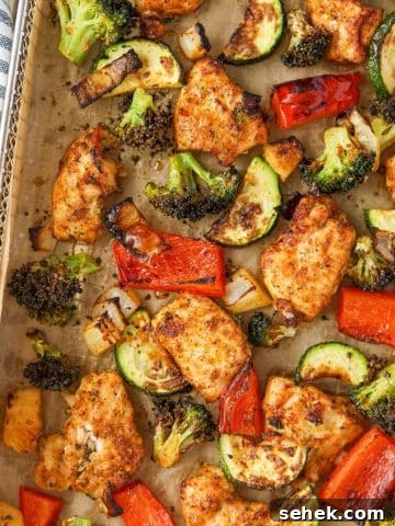 An air fryer tray filled with chicken pieces and vegetables.