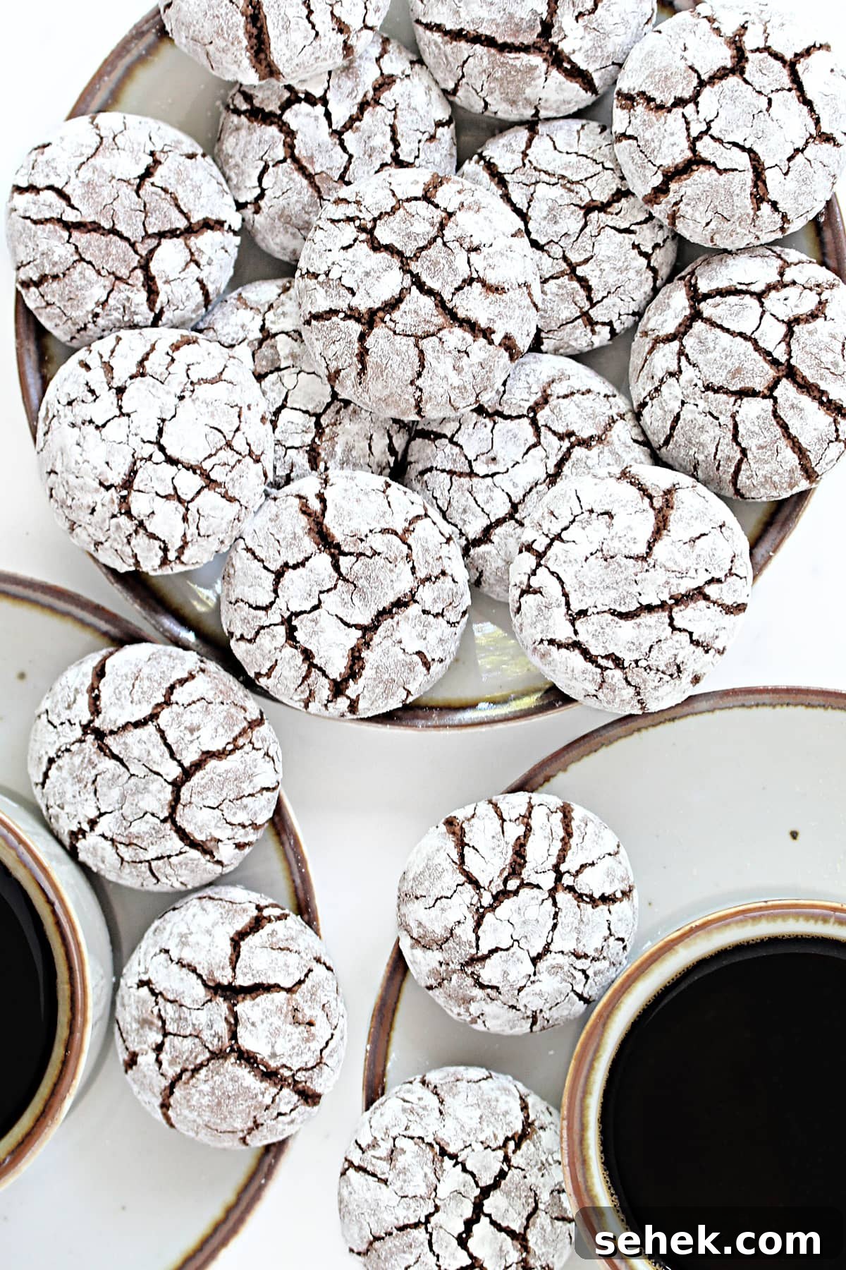 Thick round cookies covered in powdered sugar with cracks that show chocolate cookie underneath.