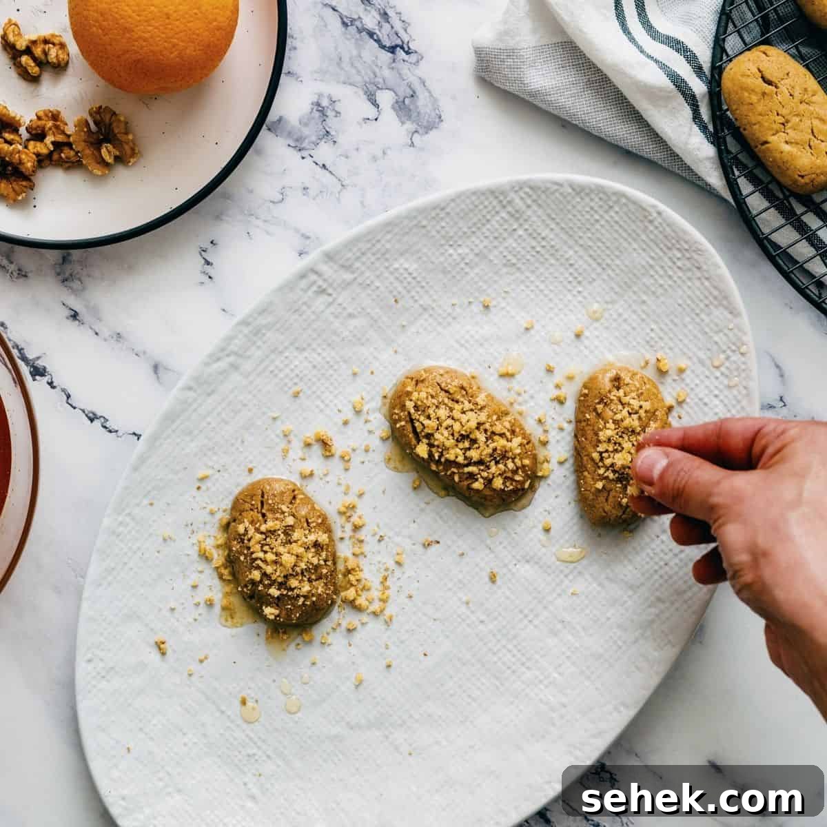 Melomakarona Greek Christmas Honey Cookies Recipe 11 placing walnuts on top of melomakarona.