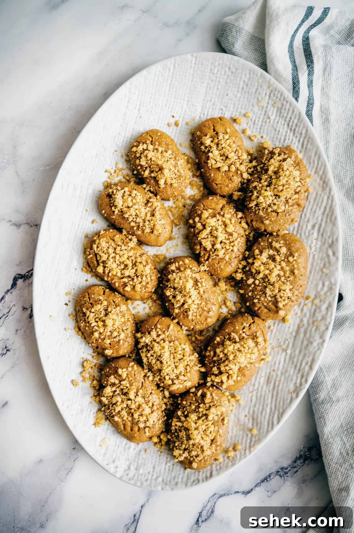 Melomakarona Greek Christmas Honey Cookies Recipe 12 a white plate filled with Greek honey cookies topped with walnuts.