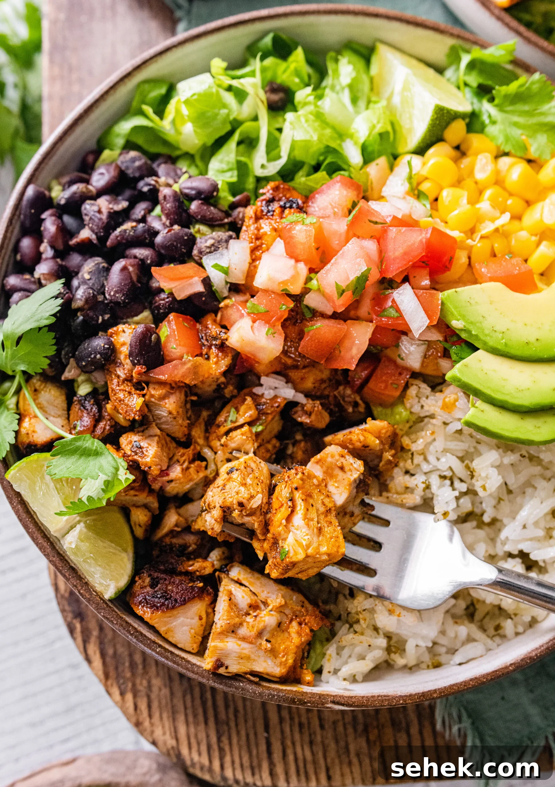Chipotle-Style Pollo Asado Recipe: Juicy Mexican Grilled Chicken 2 Pollo Asado Recipe (Chipotle Copycat) made into a rice bowl with sides with fork taking a bite.
