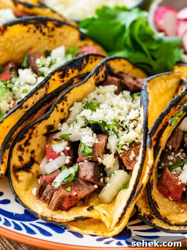 Chipotle-Style Pollo Asado Recipe: Juicy Mexican Grilled Chicken 14 Multiple tacos filled with tacos presented on a plate, with more taco toppings on the side.
