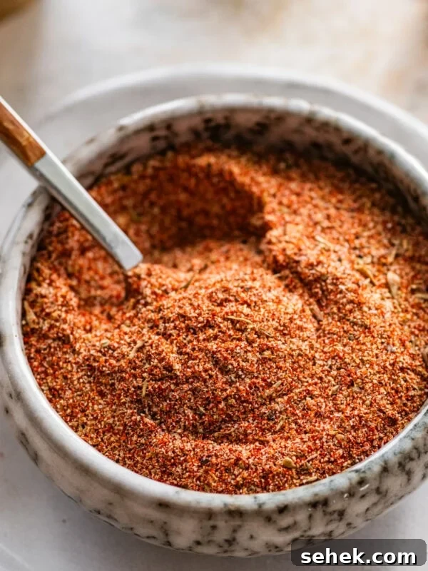Chipotle-Style Pollo Asado Recipe: Juicy Mexican Grilled Chicken 17 blackened seasoning in a white bowl with a spoon in it.