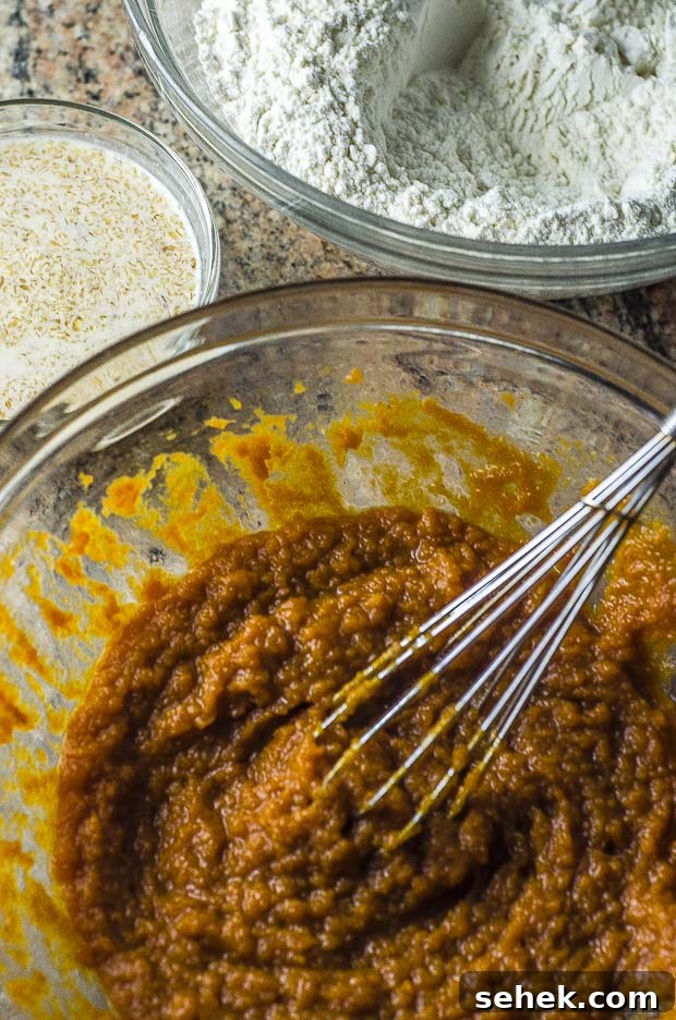 Moist Vegan Pumpkin Muffins with Warm Spices 3 Ingredients to prepare the batter for Vegan pumpkin muffins. There are three bowl one with pumpkin, another with flower and a smaller one with a flax egg which is almond milk and ground fox seeds mixed into a paste