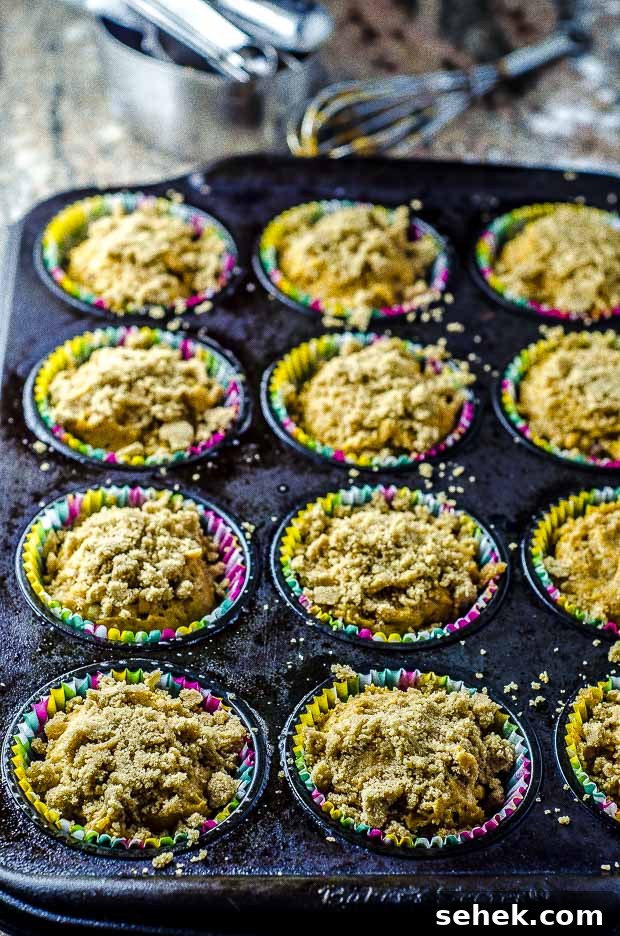 Moist Vegan Pumpkin Muffins with Warm Spices 4 Vegan pumpkin muffin batter top with a streusel in a muffin tin lined with multicolor muffin tin liners.