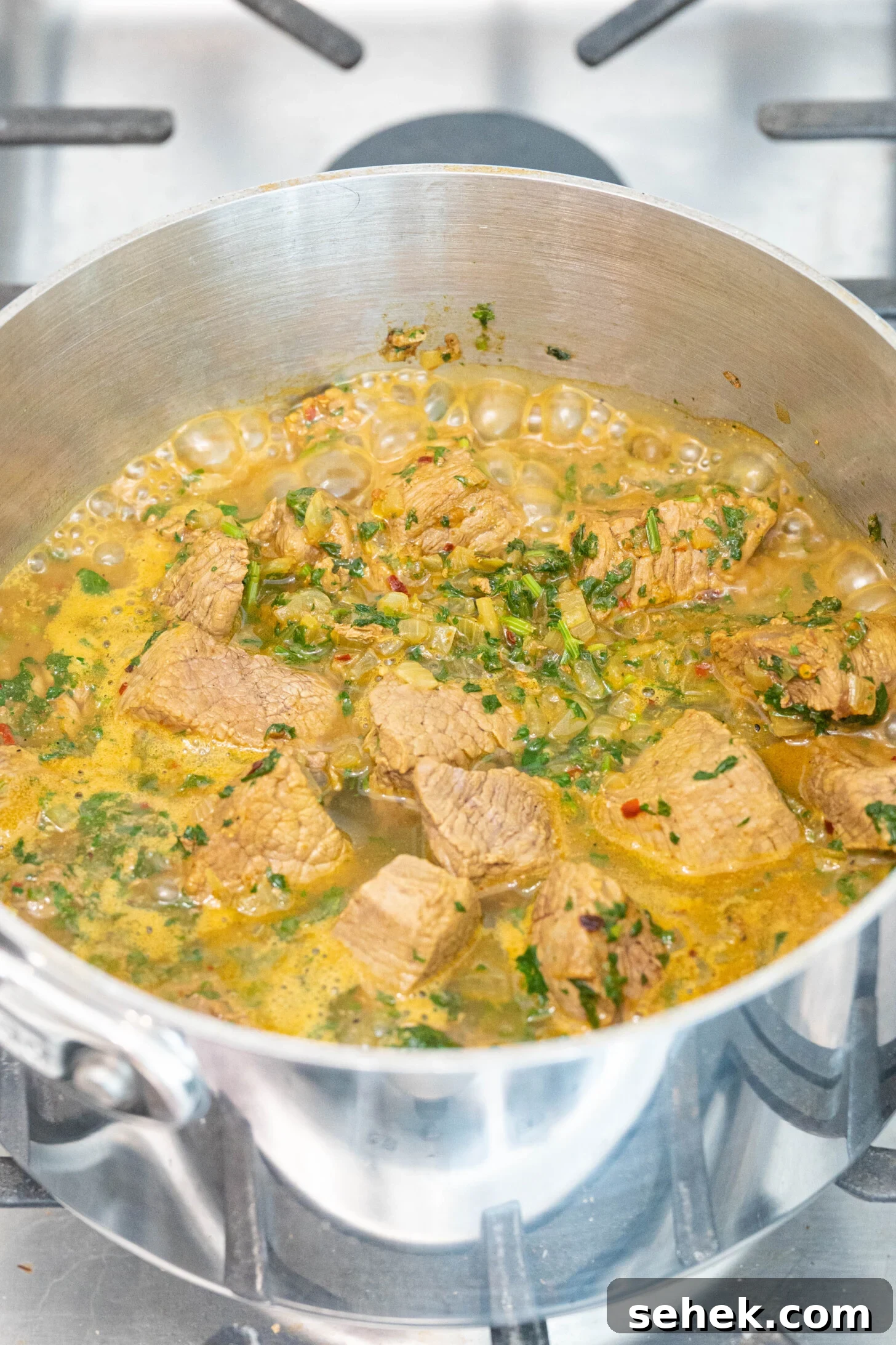 Moroccan Lamb and Orzo Recipe with Warm Spices 6 a pot with lamb, onions, herbs, and water boiling