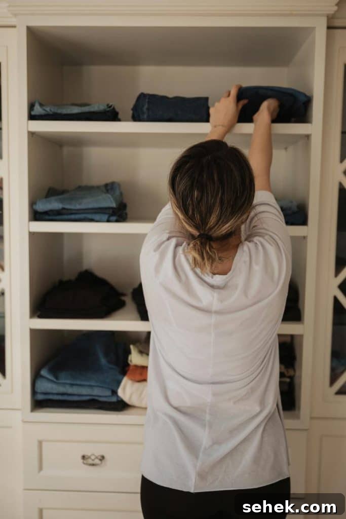 woman putting clothes on shelves in closet