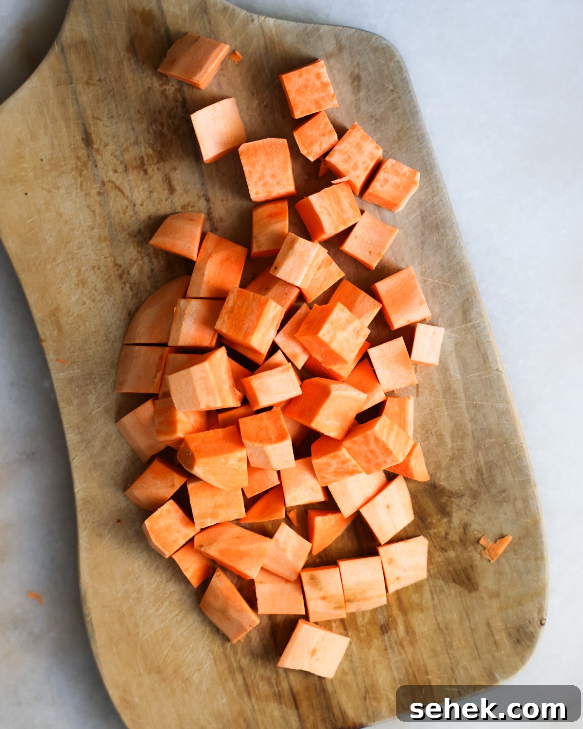 Perfectly Roasted Sweet Potatoes: Crispy Edges & Tender Centers 5 Cubed sweet potatoes on cutting board.