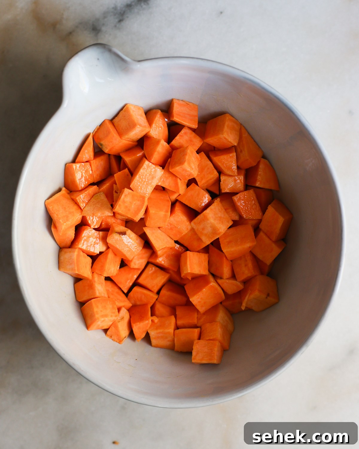 Perfectly Roasted Sweet Potatoes: Crispy Edges & Tender Centers 6 Sweet potato cubes in a mixing bowl.