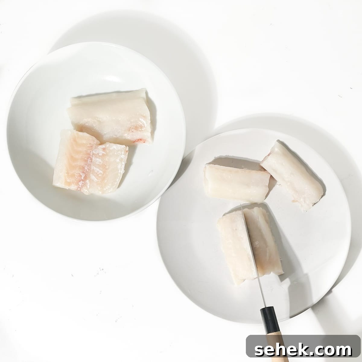 Crispy Fish Goujons Recipe — Crunchy Baked or Fried Fish Sticks 5 Cutting the fish fillets lengthways on a white plate.