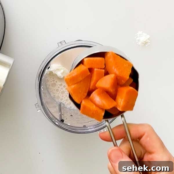 High-Protein Chocolate Sweet Potato Smoothie Recipe 7 Adding diced sweet potatoes to a blender cup.