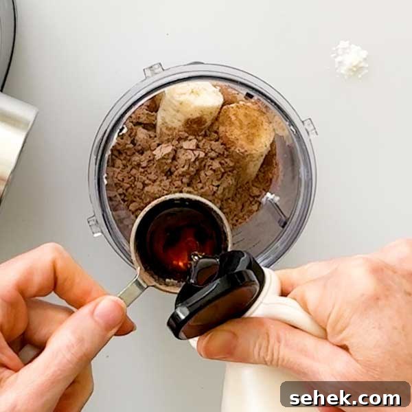 High-Protein Chocolate Sweet Potato Smoothie Recipe 8 Adding maple syrup to a blender cup.