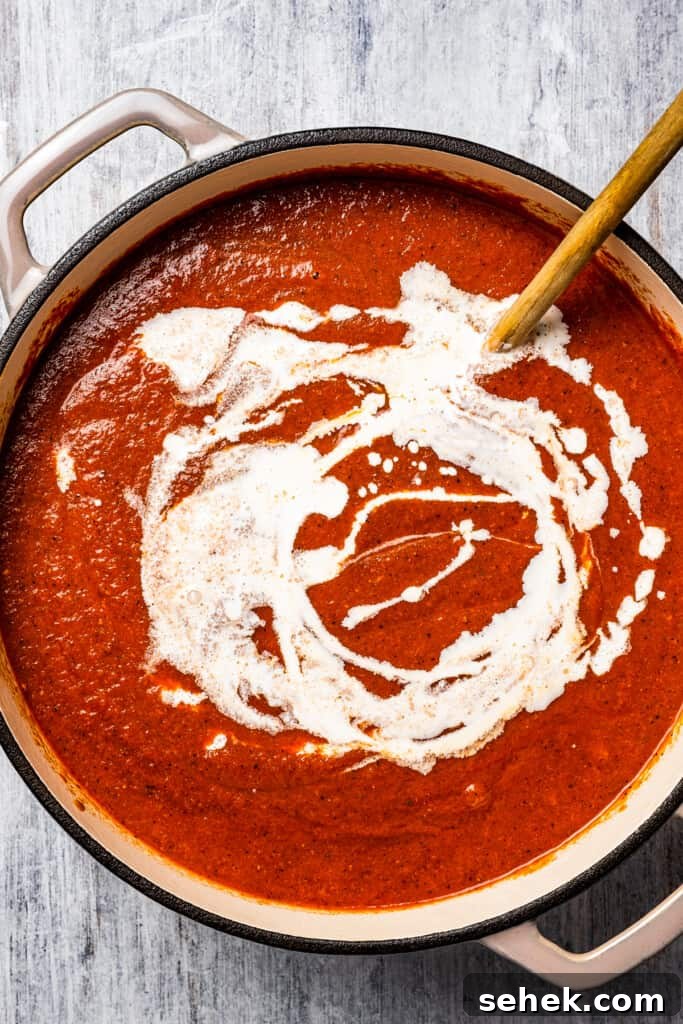 Make the slurry. Adding the heavy cream-cornstarch slurry to a tomato soup.