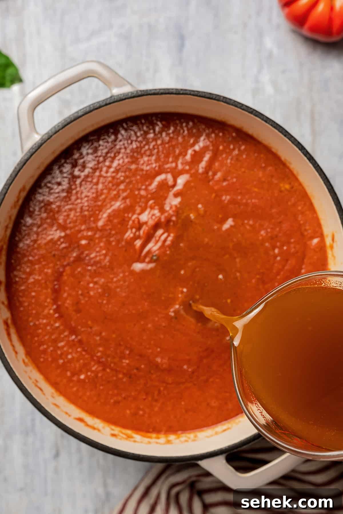 Add the broth and simmer. Pouring in the broth.