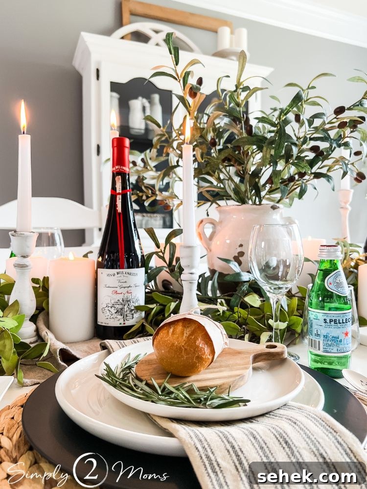 Italian-Inspired Tablescape Ideas for Elegant Dinner Parties 5 A plate with rosemary, dinner roll, and linen napkin on table decorated with candles, olive stems, and a wine bottle