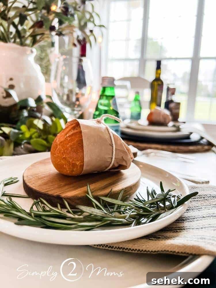 Italian-Inspired Tablescape Ideas for Elegant Dinner Parties 6 roll wrapped in tissue on mini cutting board with sprig of rosemary on plate