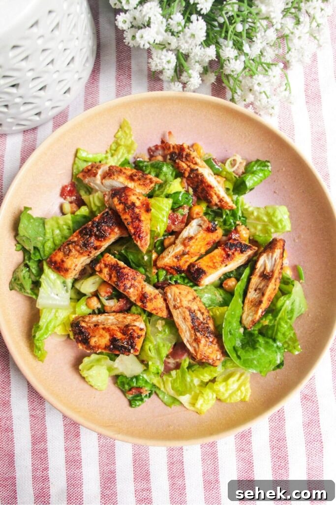 Sliced chicken on top of lettuce in a pink bowl.