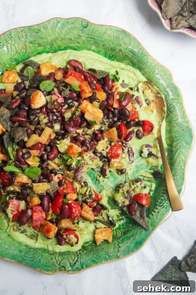 Mexican bean salad on top of whipped avocado on a large green platter.