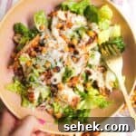 Hand holding a pink bowl filled with grilled chicken Caesar salad.