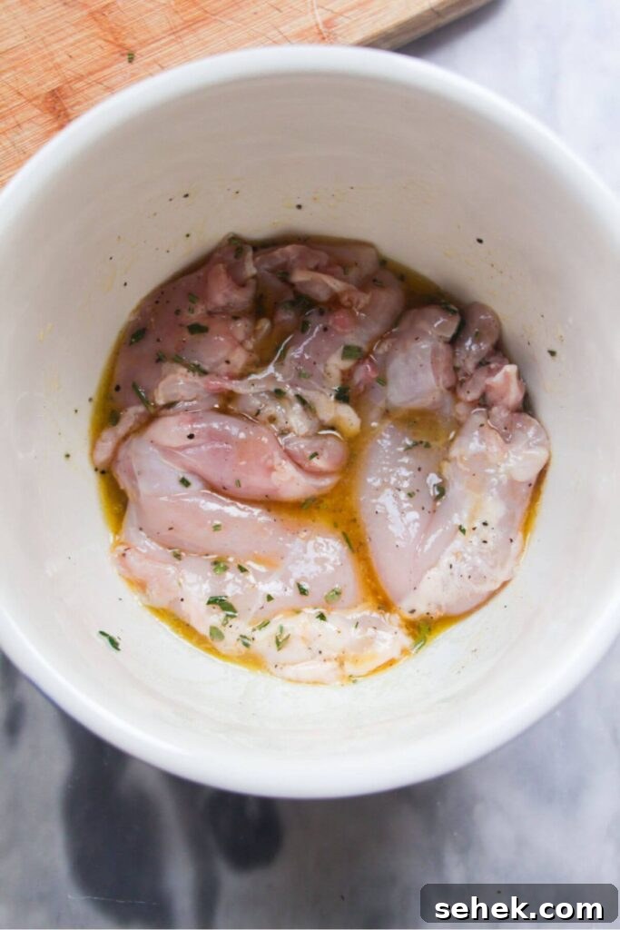 Chicken thighs marinating in a small white bowl.