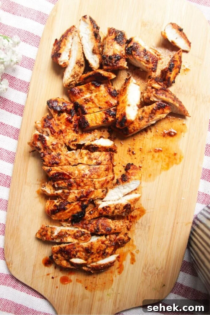 Sliced charred chicken on a wooden board.