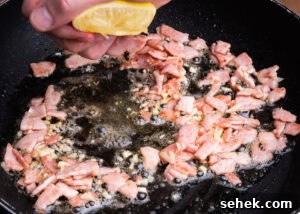 Garlic Green Beans with Crispy Bacon and Lemon Zest 12 Squeezing lemon juice on top of bacon and garlic cooking in butter in a frying pan