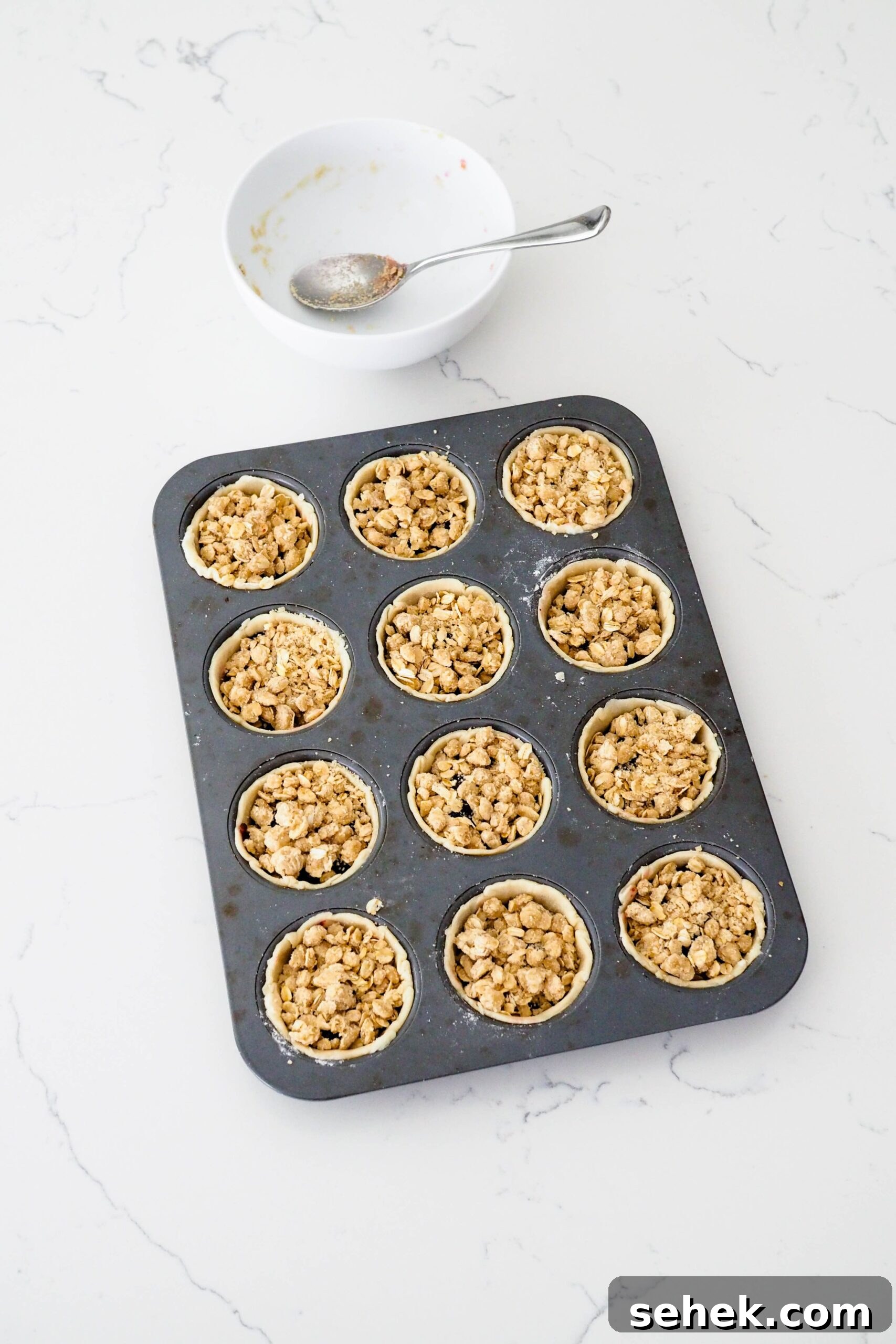 Mini Blueberry Hand Pies: Bite-Sized Fruit Desserts for Any Occasion 10 Mini blueberry pies in a muffin pan right before baking.