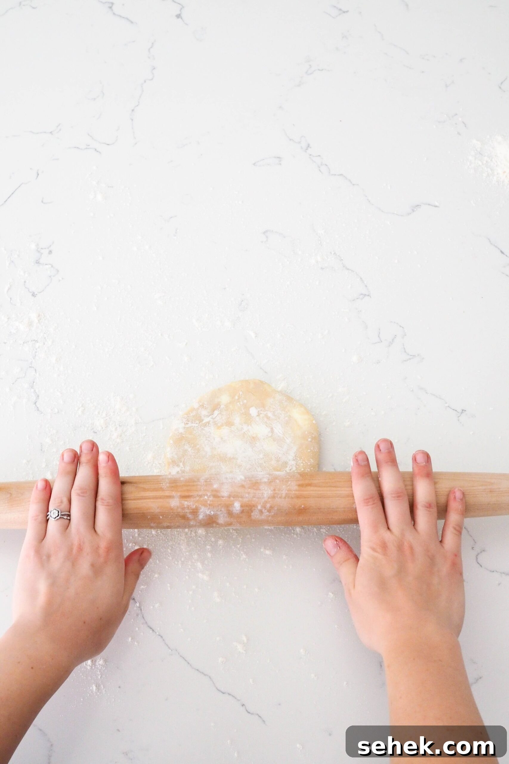 Mini Blueberry Hand Pies: Bite-Sized Fruit Desserts for Any Occasion 6 Two hands push a rolling pin over a pie crust.