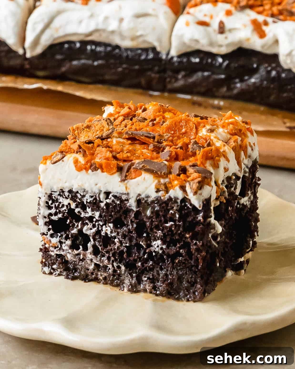 Butterfinger cake is a decadent poke cake made from moist chocolate or yellow cake, filled with gooey caramel sauce, topped with whipped topping and crushed butterfinger candy. This butterfinger candy bar cake comes together quickly and easily, making this the perfect dessert for potlucks, gatherings and celebrations.