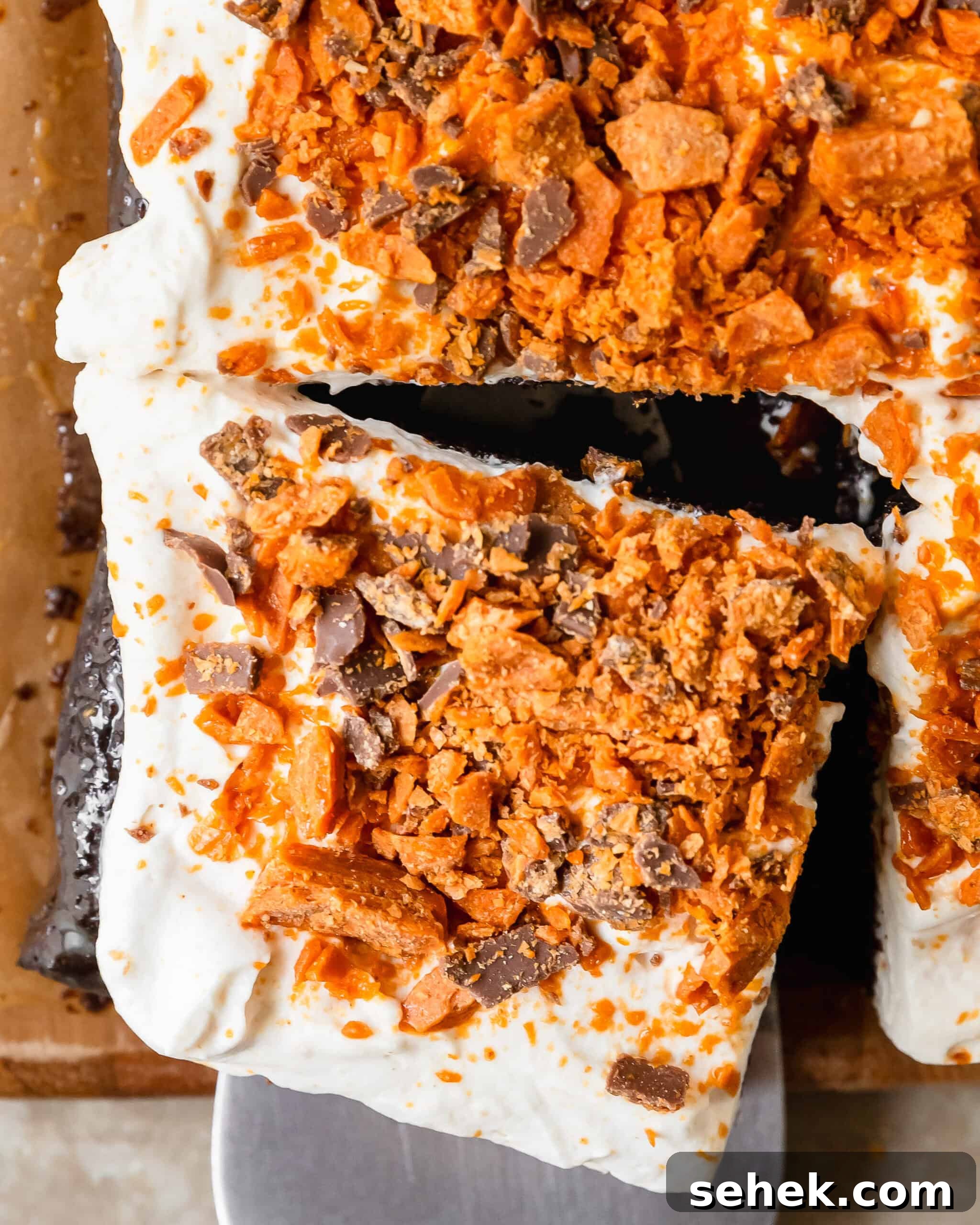 Butterfinger cake is a decadent poke cake made from moist chocolate or yellow cake, filled with gooey caramel sauce, topped with whipped topping and crushed butterfinger candy. This butterfinger candy bar cake comes together quickly and easily, making this the perfect dessert for potlucks, gatherings and celebrations