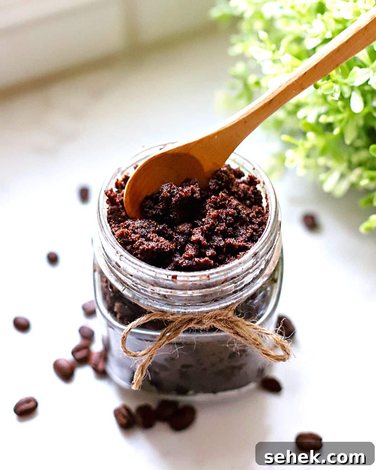 DIY Coffee Sugar Scrub Recipe for Smooth, Glowing Skin 2 A coffee sugar scrub in a glass jar with a spoon sticking out of it.
