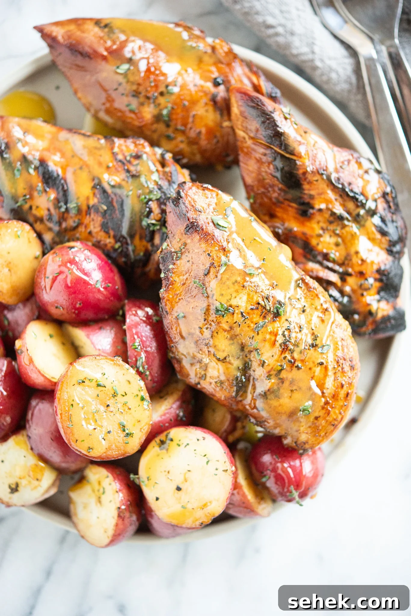 Instant Pot Honey Mustard Chicken with Roasted Potatoes 9 Seared honey mustard chicken and halved red potatoes on a grey plate on a marble surface