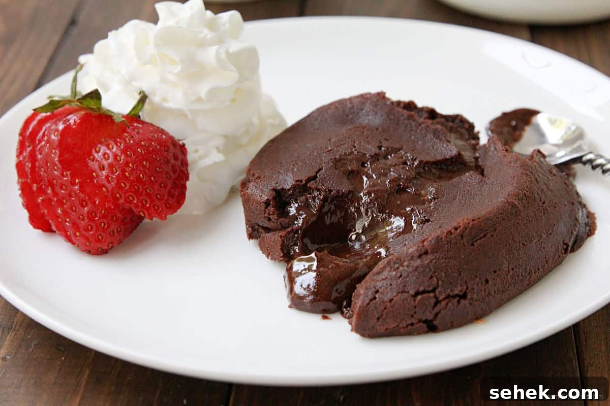 Chocolate Molten Lava Cake Chocolate Molten Lava Cake with spoon, strawberry, and whipped cream on plate