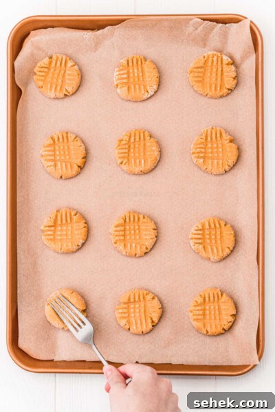 Chewy Peanut Butter Cookies with Crispy Edges: Simple Recipe 12 fork pressing peanut butter cookies flat with a criss cross pattern