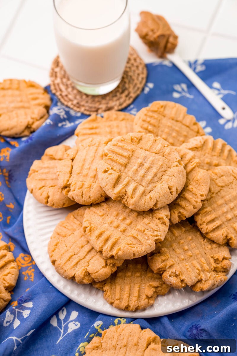Chewy Peanut Butter Cookies with Crispy Edges: Simple Recipe 3 side view of peanut butter cookies on a plate next to milk and a spoon of peanut butter