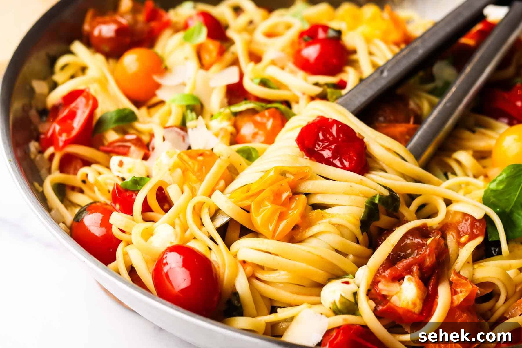 Quick Cherry Tomato Pasta with Garlic and Basil 3 cherry tomato pasta in a skillet with a tong inside it.
