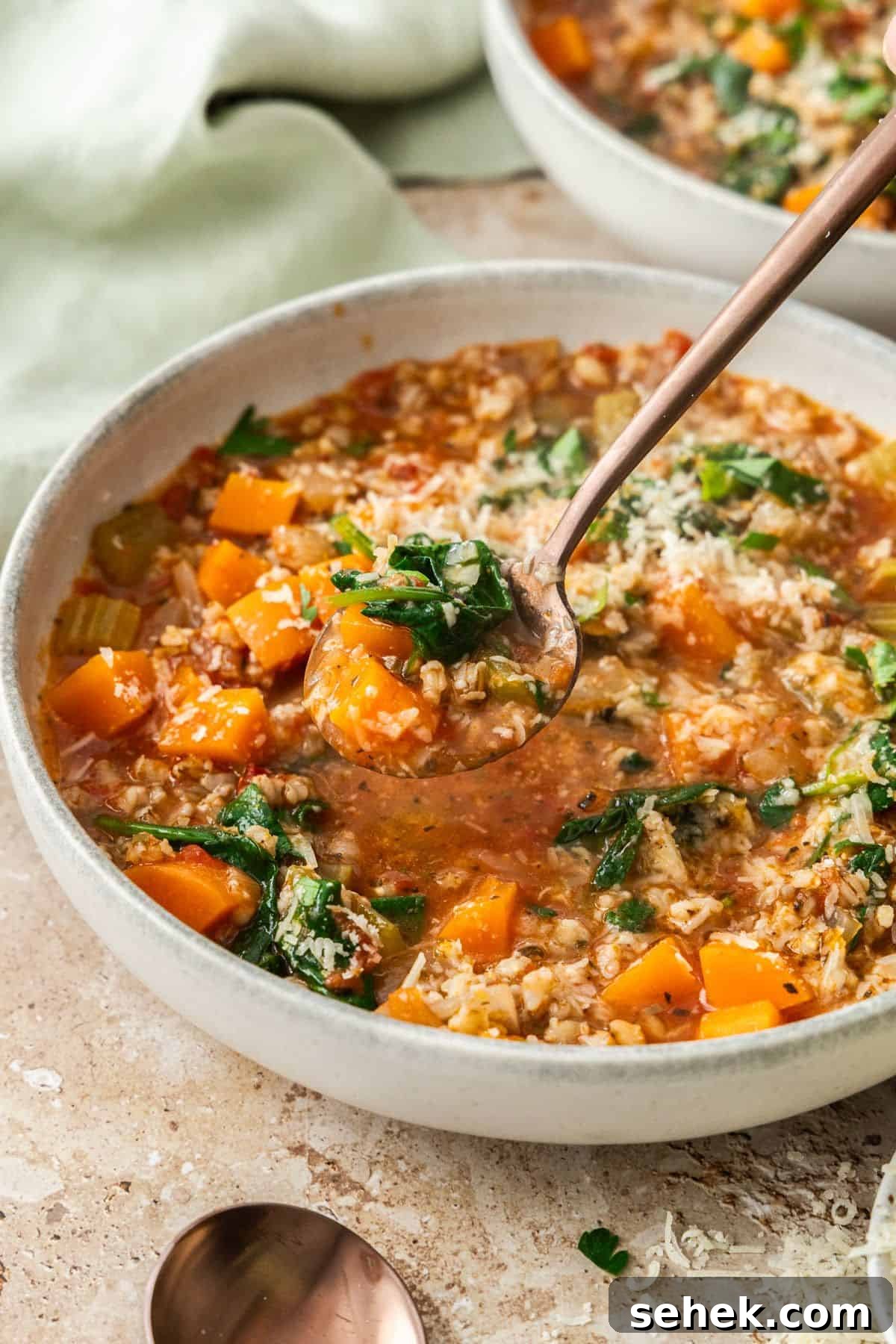 Mediterranean Barley Vegetable Soup Recipe for Flavorful Comfort 8 Bowl of Vegetable and Barley Soup, with a spoon lifting up a mouthful of soup.