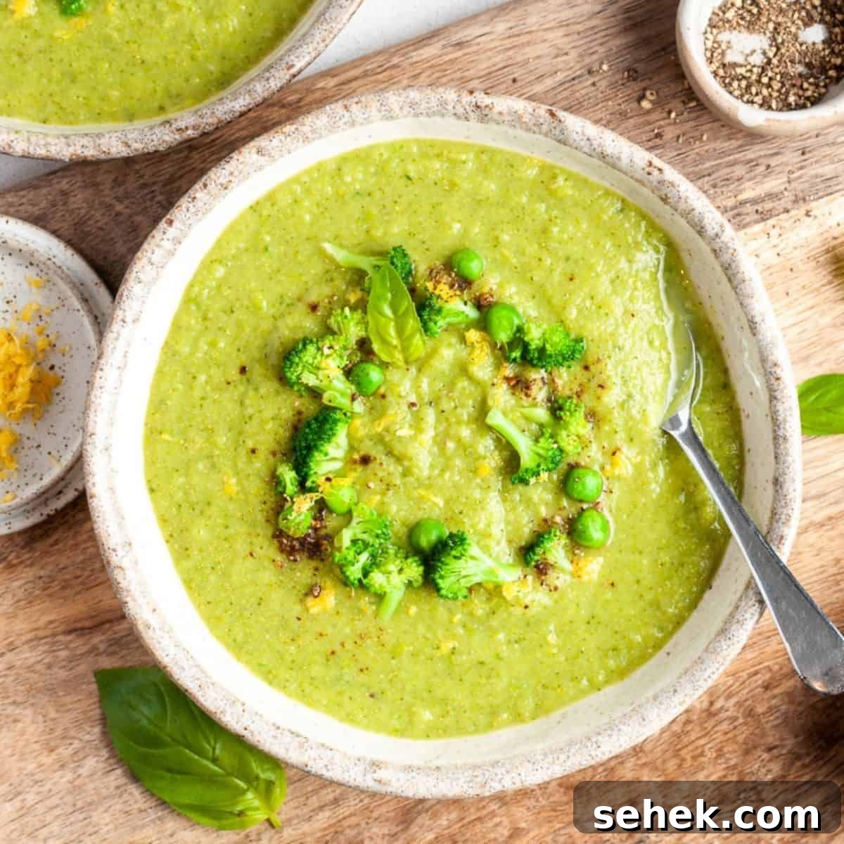 Two bowls of soup, one sitting on a wooden board.