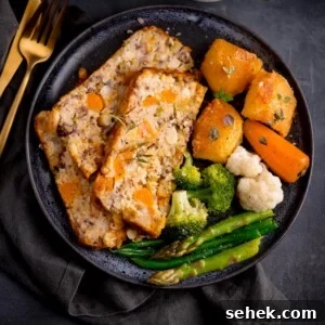 Savory Vegetarian Nut Roast Recipe for Holiday Dinner 7 Three slices of vegetarian nut roast on a dark blue plate with vegetable and potatoes.