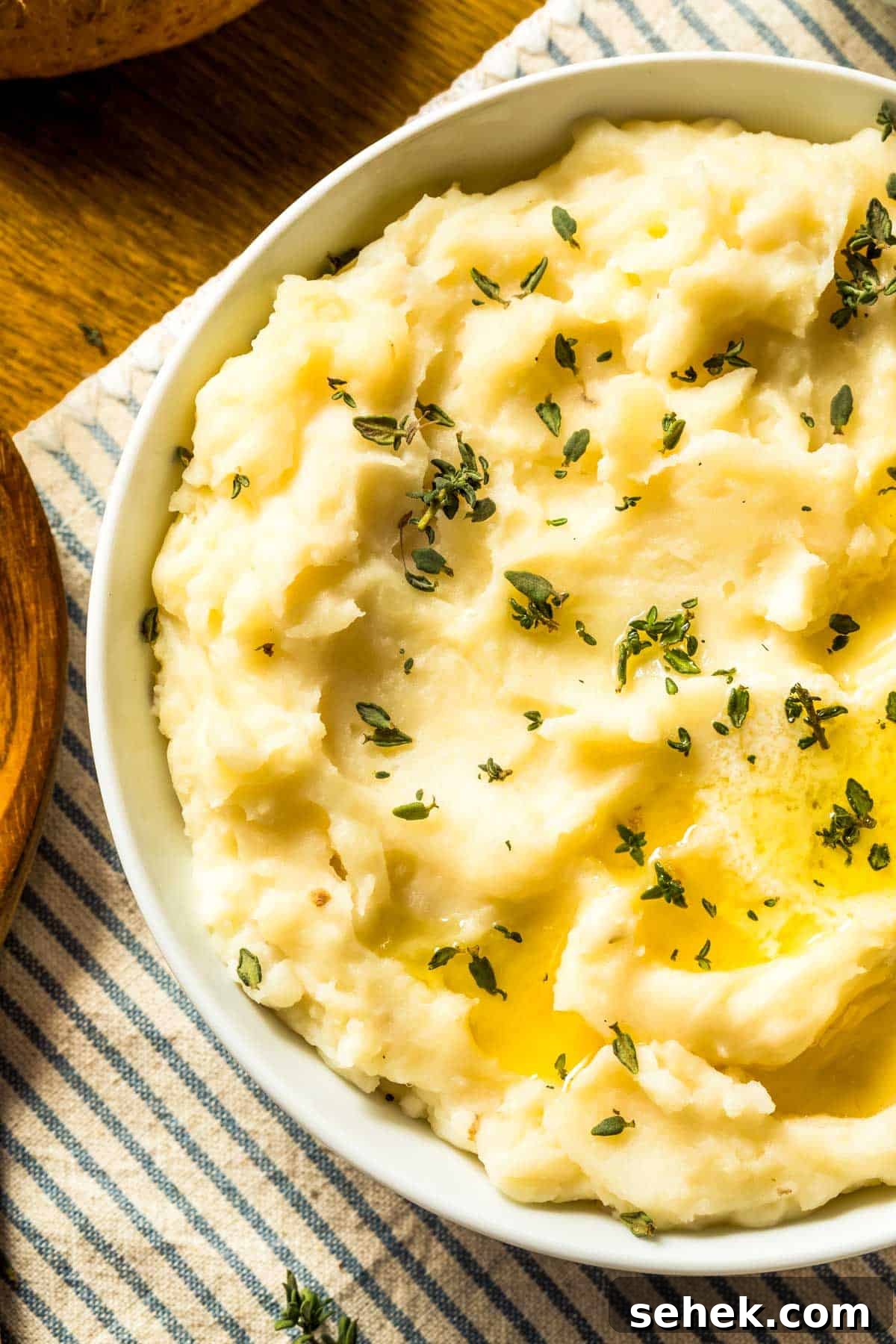 How to Make Silky Mashed Potatoes That Melt in Your Mouth 2 a white bowl filled with easy mashed potatoes and garnished with fresh thyme leaves