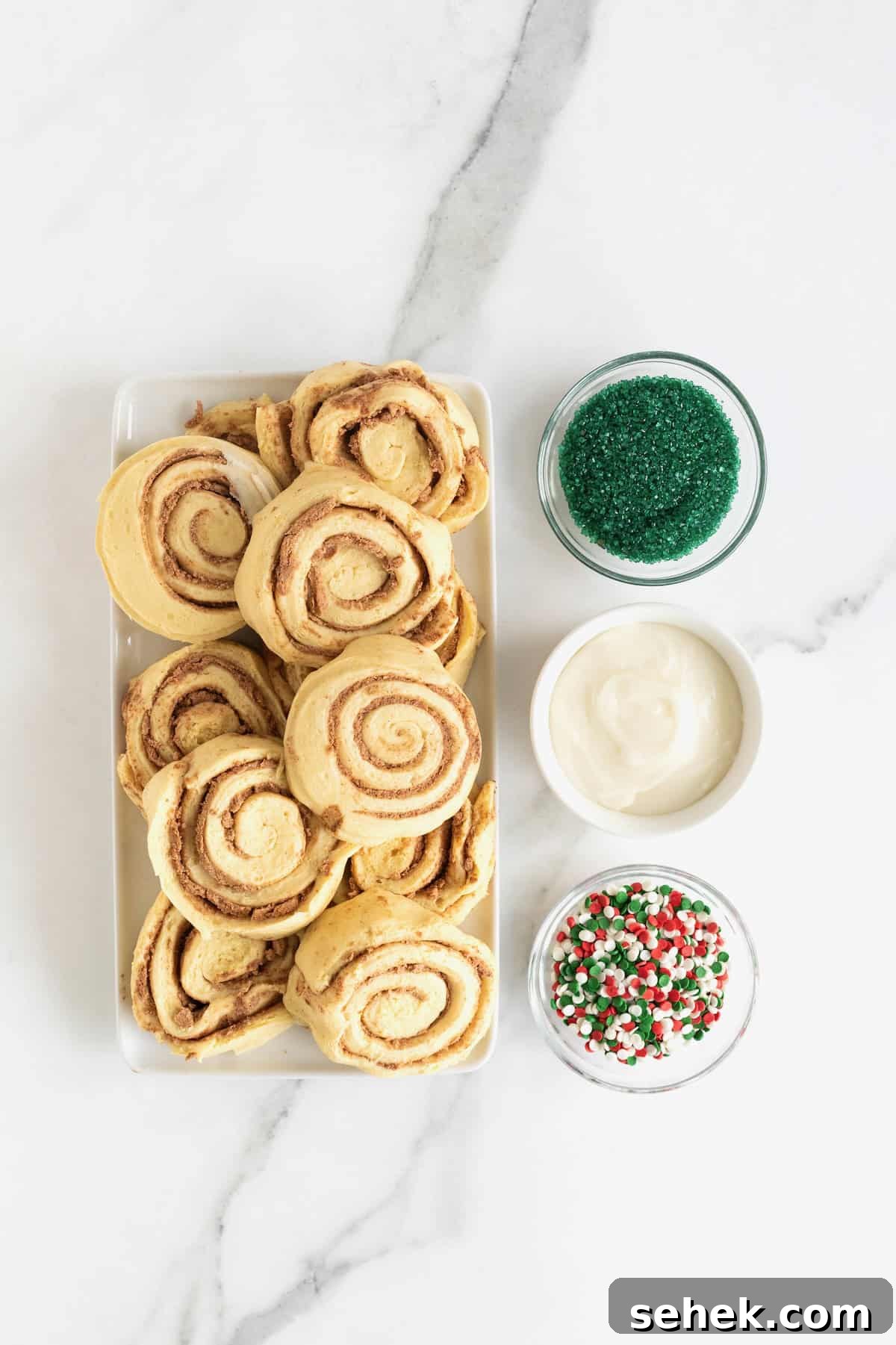 Cinnamon Roll Christmas Tree Pull-Apart Recipe 6 Ingredients to make a Christmas tree cinnamon roll in white dishes on a white marble counter.