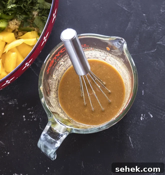 Thai Quinoa Mango Salad with Peanut Ginger Dressing 7 peanut ginger dressing in a measuring jar with a whisk
