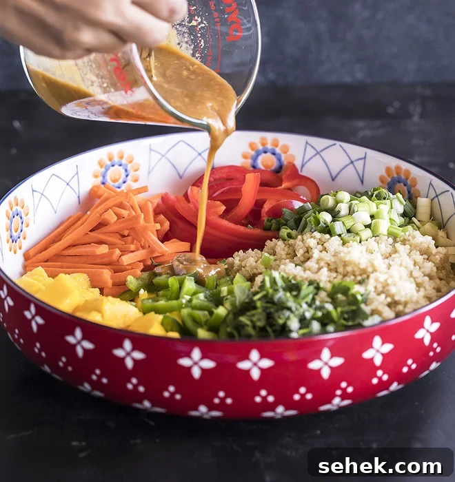 Thai Quinoa Mango Salad with Peanut Ginger Dressing 8 peanut ginger dressing being poured over a big bowl of quinoa salad