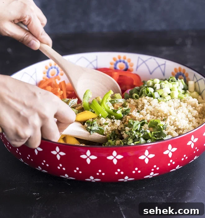 Thai Quinoa Mango Salad with Peanut Ginger Dressing 9 quinoa mango salad in a large bowl being tossed with two wooden spoons