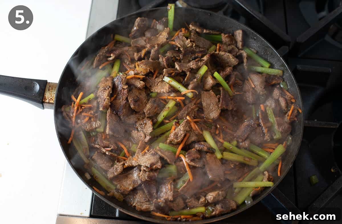 Sizzling Beef Stir-Fry with Shredded Vegetables and Ginger 8 Beef, carrots, and peppers cooking in a skillet