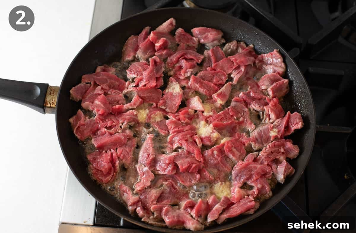 Sizzling Beef Stir-Fry with Shredded Vegetables and Ginger 5 Beef cooking in a skillet, turning from raw to half-way cooked