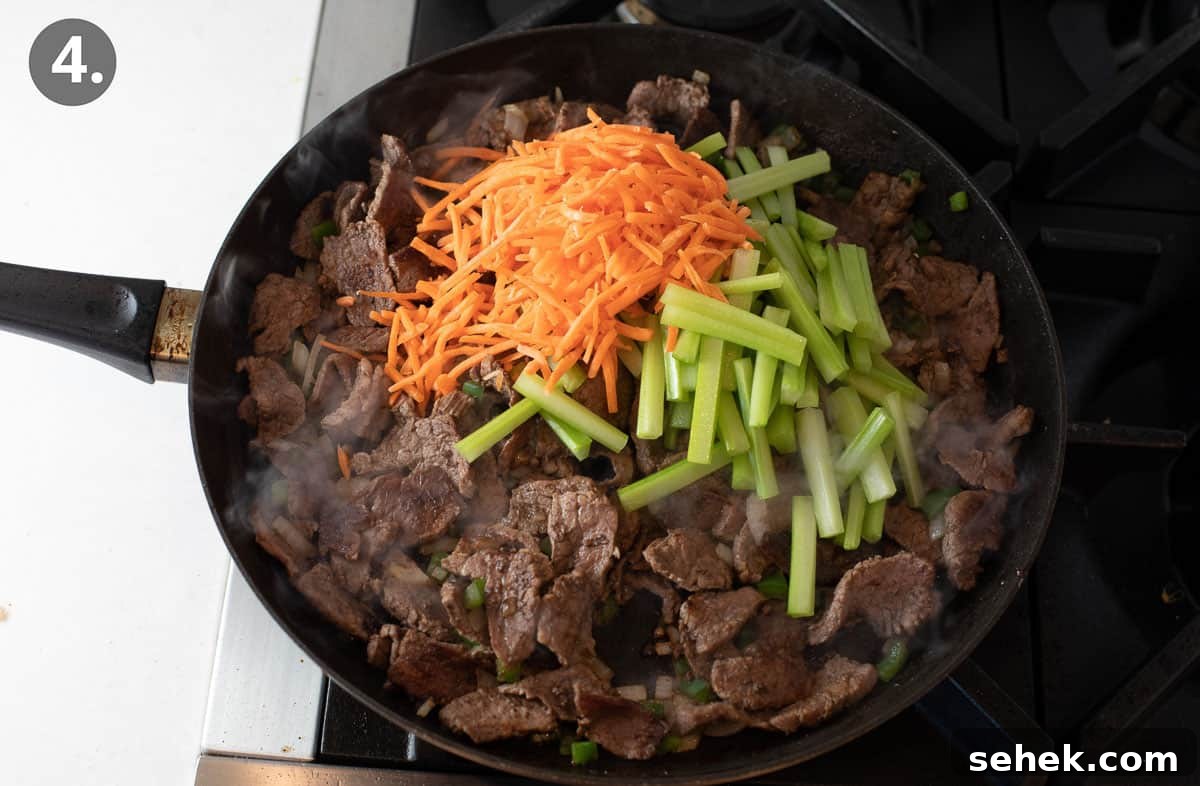 Sizzling Beef Stir-Fry with Shredded Vegetables and Ginger 7 Beef cooking in a skillet, with shredded carrots and peppers on top