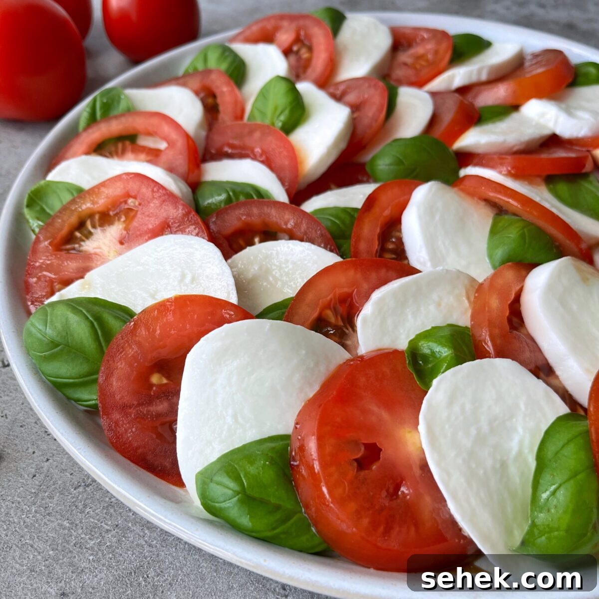Classic Tomato Caprese Salad with Fresh Basil and Mozzarella 3 A side view of a Tomato Caprese Salad featuring alternating slices of tomato, mozzarella cheese, and fresh basil leaves arranged in a beautiful circular pattern.